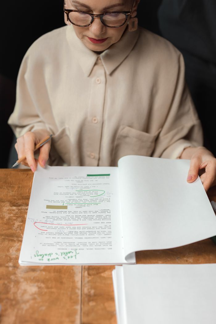 services-03 Senior woman reviewing a screenplay script with notes and edits, showcasing expertise.